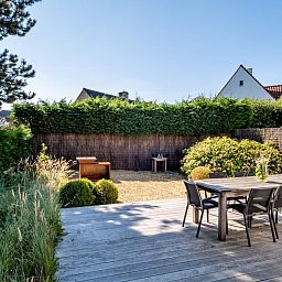 Geniet van de serene veranda bij vakantiehuis Tranquil in Koksijde, West-Vlaanderen, omgeven door groene natuur en rustgevende tuinen.