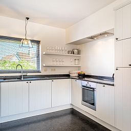 Moderne keuken in vakantiehuis Tranquil, Koksijde, West-Vlaanderen, met strakke inrichting en veel natuurlijk licht.