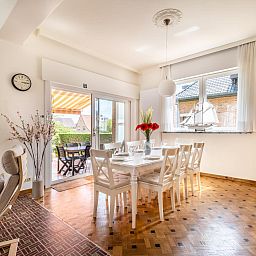 Lichte eetkamer in vakantiehuis Porpoises, Koksijde, met uitzicht op zonnig terras en tuin, ideaal voor een ontspannen verblijf in West-Vlaanderen.