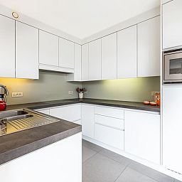 Moderne keuken in Tinou Gelijkvloers vakantiehuis in Koksijde, West-Vlaanderen, met strakke witte kasten en ruime werkbladen.