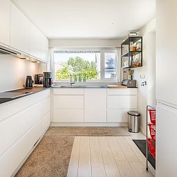 Moderne keuken in vakantiehuis Guillaume in Koksijde, West-Vlaanderen, met uitzicht op groene omgeving en strakke inrichting.