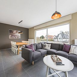 Stylish living room of vacation home La Vachequirit in Koksijde, West Flanders with comfortable seating area and large windows for plenty of light.