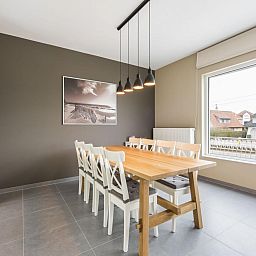 Dining room of vacation home La Vachequirit in Koksijde, West Flanders, with large table and view of the peaceful surroundings.