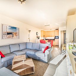 Gezellige woonkamer van vakantiehuis Pablito trois in Koksijde, West-Vlaanderen, met comfortabele bank en moderne keuken.