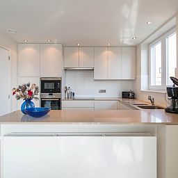 Moderne keuken in vakantiehuis Bon Accueil tweede in Koksijde, West-Vlaanderen, Belgie, met strakke witte kasten en veel natuurlijk licht.