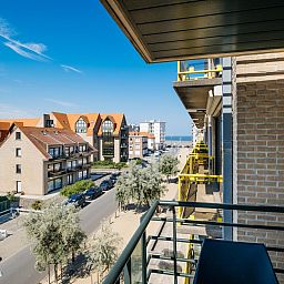 Uitzicht vanaf het balkon van vakantiehuis Paco vierde in Koksijde, West-Vlaanderen, met zicht op de kust en omliggende architectuur.