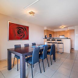 Ruime eetkamer en keuken in vakantiehuis Paco Vierde, Koksijde, West-Vlaanderen. Gezellige binnenruimte met moderne inrichting en kunstwerk.