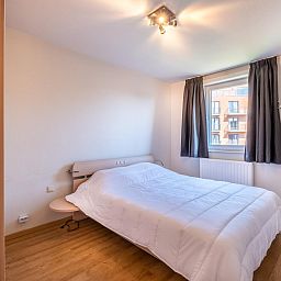Gezellige slaapkamer in vakantiehuis Paco Vierde, Koksijde, West-Vlaanderen, met comfortabel bed en natuurlijk licht door het raam.