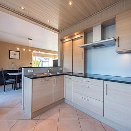 Moderne keuken in vakantiehuis Mallory in Koksijde, West-Vlaanderen, met houten kasten en ruime eetkamer, ideaal voor een ontspannen verblijf.