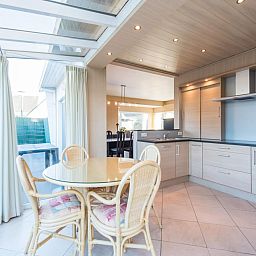 Lichte keuken en eetruimte in vakantiehuis Mallory, Koksijde, West-Vlaanderen. Moderne inrichting met glazen dak en gezellige eethoek.