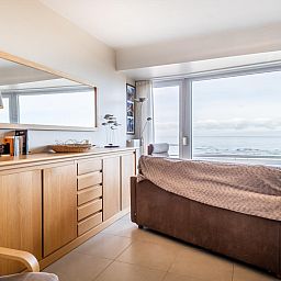 Gezellige woonkamer van Vitelli vierde vakantiehuis in Koksijde, West-Vlaanderen met panoramisch uitzicht op zee en moderne inrichting.