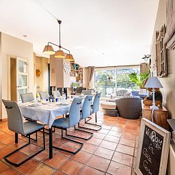 Ruime eetkamer in vakantiehuis Le Palmier in Koksijde, West-Vlaanderen, met uitzicht op tuin en comfortabele inrichting.