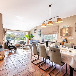 Gezellige woonkamer van vakantiehuis Le Palmier in Koksijde, West-Vlaanderen, met eethoek en uitzicht op de tuin.