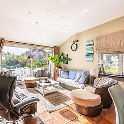 Gezellige woonkamer van vakantiehuis Le Palmier in Koksijde, West-Vlaanderen, met zonovergoten terras en moderne inrichting.