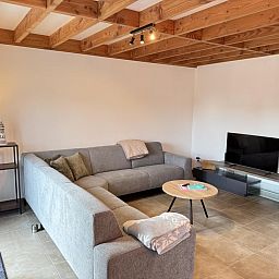 Gezellige woonkamer van vakantiehuis Westhinder II H23 in Koksijde, West-Vlaanderen, met comfortabele zithoek en moderne inrichting.