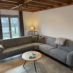 Gezellige woonkamer in vakantiehuis Westhinder II H23, Koksijde, met comfortabele zithoek en moderne inrichting.