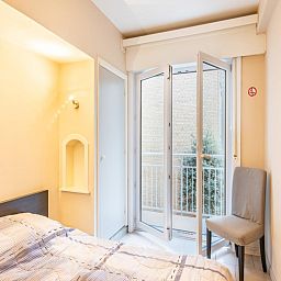 Slaapkamer in vakantiehuis Vitelli in Koksijde, West-Vlaanderen met balkon en natuurlijk licht.