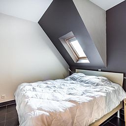 Sfeervolle slaapkamer in Le Penthouse, een vakantiehuis in Koksijde, West-Vlaanderen, met een dakraam voor natuurlijk licht.