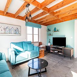 Gezellige woonkamer in vakantiehuis Westhinder I H12, Koksijde, met houten balkenplafond en moderne inrichting, West-Vlaanderen, Belgie.