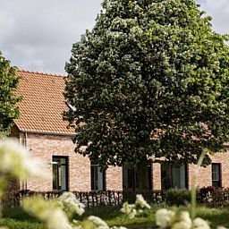 Ferienhaus 't hov in Passchendaele, umgeben von ueppiger Natur und schattigen Baeumen.