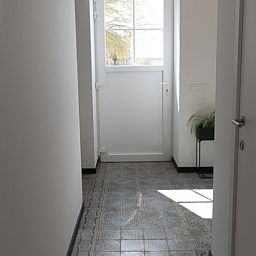 Heller Eingang zum Ferienhaus 't hov in Passendale mit stilvollem Fliesenboden und modernen Moebeln.