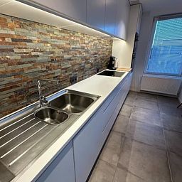 Moderne Kueche in der Wohnung Memling, einer Wohnung in Sint-Andries, Westflandern, Belgien, mit stilvollem Dekor und eleganten Oberflaechen.