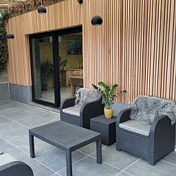 Gemuetliche Terrasse des Cottage in Ingooigem, Ferienunterkunft in Westflandern, mit Sitzgelegenheiten und gruener Umgebung.