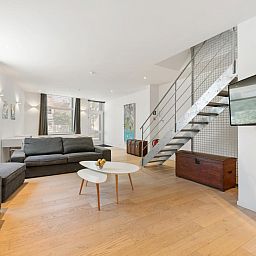 Stilvolles Wohnzimmer in "De Loft", einem Ferienhaus in Veurne, Westflandern, mit moderner Einrichtung und viel Tageslicht.