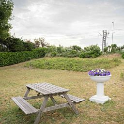 Rustieke tuin van Charmevilla Westende in Westende, Belgie, met picknicktafel en groene omgeving voor een ontspannen vakantiehuiservaring.