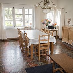 Gezellige woonkamer in Charmevilla Westende, een vakantiehuis in Westende, West-Vlaanderen, met ruime eettafel en rustieke inrichting.