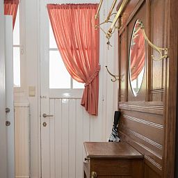 Ontvangstruimte van Charmevilla Westende, een vakantiehuis in Westende, Belgie, met vintage houten meubels en kleurrijke tegels.