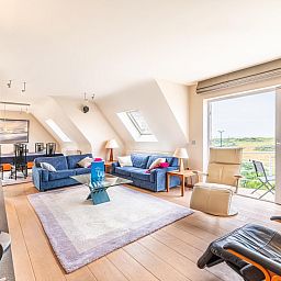 Helles Wohnzimmer des Ferienhauses LaRoyale in De Panne, Westflandern, mit komfortabler Einrichtung und Blick auf die natuerliche Umgebung.