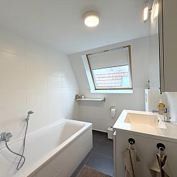 Modernes Badezimmer des Home Sweet Home Ferienhauses in De Panne, Westflandern, mit Badewanne und Tageslicht.