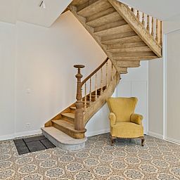 Diele von Maison Perron, Ferienhaus De Panne, Westflandern mit Holztreppe und altem Stuhl.