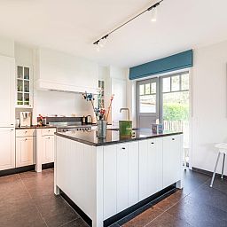 Moderne keuken in vakantiehuis La Matinee, Sint-Idesbald, West-Vlaanderen met ruime kookeiland en tuinzicht.