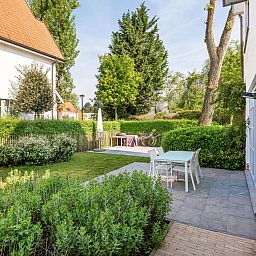 Geniet van de serene tuin van vakantiehuis La Matinee in Sint-Idesbald, West-Vlaanderen, met terras en groene omgeving.