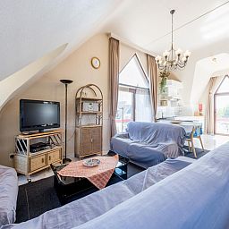 Gezellige woonkamer van vakantiehuis Aubepine troisieme in Sint-Idesbald, West-Vlaanderen, met comfortabele zithoek en veel natuurlijk licht.