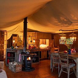 Gezellige binnenruimte van Tenthuisje met warme privedouche in Zedelgem, West-Vlaanderen, Belgie, met rustieke meubels en sfeerverlichting.