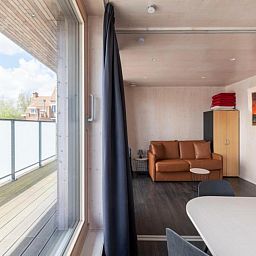 Gemuetlicher Innenbereich der Kruiers Eco Lodge in Middelkerke, Westflandern, mit Blick auf die Terrasse und den gemuetlichen Sitzbereich.