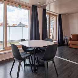 Gemuetlicher Innenbereich der Kruiers Eco Lodge in Middelkerke, Westflandern, mit einem modernen Essbereich und grossen Fenstern fuer viel natuerliches Licht.