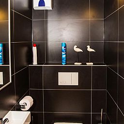 Modernes Badezimmer im Ferienhaus Michelangelo - 0605, Middelkerke, Westflandern, mit stilvollen schwarzen Fliesen und dekorativen Elementen.