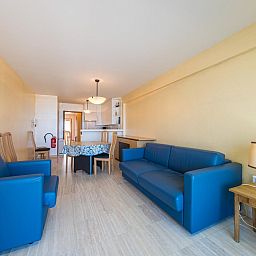 Helles Wohnzimmer im Azur Palace - 0602, Ferienhaus in Middelkerke, Westflandern, mit bequemen blauen Sofas und einer gemuetlichen Essecke.