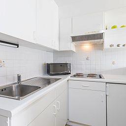 Moderne Kueche im Ferienhaus Green Garden Block 1 - 0105 in Middelkerke, Westflandern, mit weissen Schraenken und modernen Geraeten.
