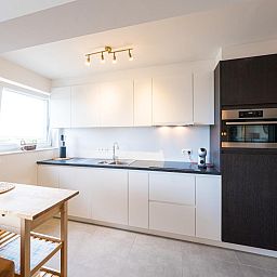 Moderne Kueche im Ferienhaus Majestic - 0505, Middelkerke, Westflandern, mit schlichten weissen Schraenken und viel natuerlichem Licht.