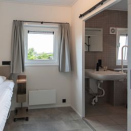 Modernes Schlafzimmer und Badezimmer in Access Lodge, einem Ferienhaus in Westende, Westflandern, mit Blick auf die gruene Umgebung.