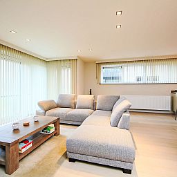 Stijlvolle woonkamer in Appartement Cocoon, Bredene, West-Vlaanderen, met moderne inrichting en veel natuurlijk licht.