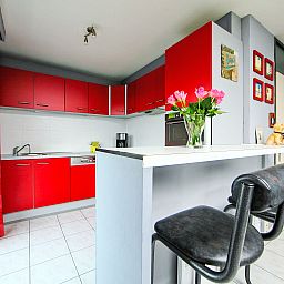 Stylish kitchen in Apartment Apt. 403, Bredene, West Flanders with modern red cabinets and a cozy bar area.