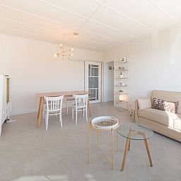 Helles und modernes Wohnzimmer der Ferienwohnung Casa Bunck in Bredene, Westflandern, mit gemuetlicher Sitzecke und Essbereich.
