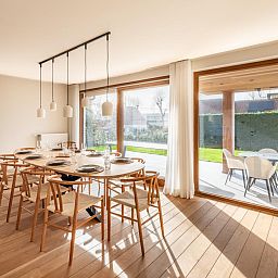 Helles Esszimmer im Ferienhaus "Pure Relax" in Oostduinkerke mit Blick auf die Terrasse und den Garten in Westflandern, Belgien.