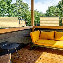 Lodge-Veranda in Gent, Ostflandern, Belgien mit bequemen Sitzgelegenheiten und Blick auf die gruene Umgebung.